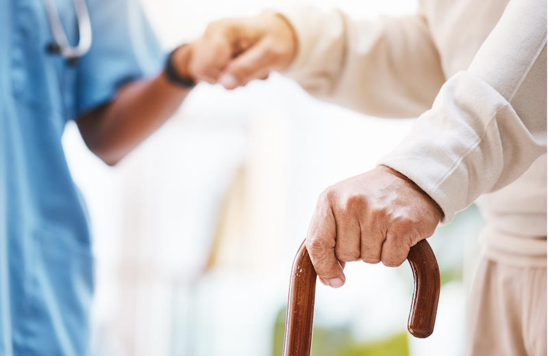 Une aide à domicile tenant la main à une personne âgée atteinte de la maladie de Parkinson