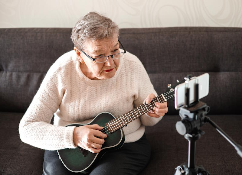 Dame de plus 70 ans apprenant l'ukulélé à la maison