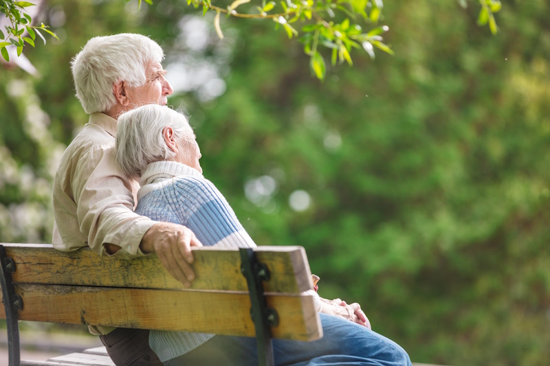 Couple âgé assis sur un banc dans le parc de l'Ehpad