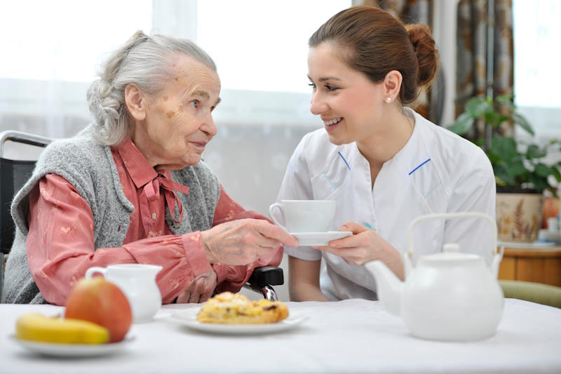 Auxiliaire de vie aidant une résidente âgée Alzheimer à manger en Ehpad