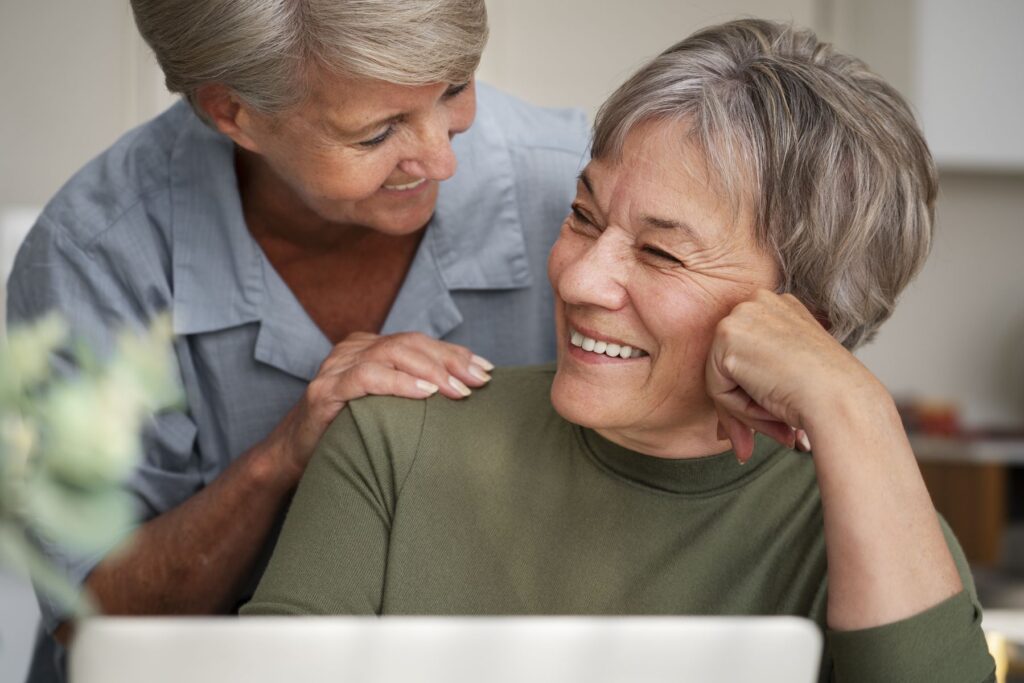 Deux femmes seniors sourient découvrant que la téléassistance donne droit à divers avantages fiscaux