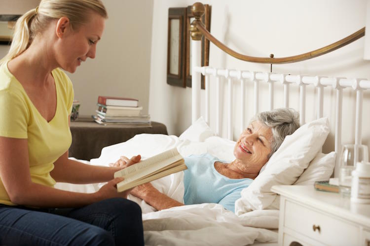 Jeunes femmes lisant à une femmes alitée en soins palliatifs
