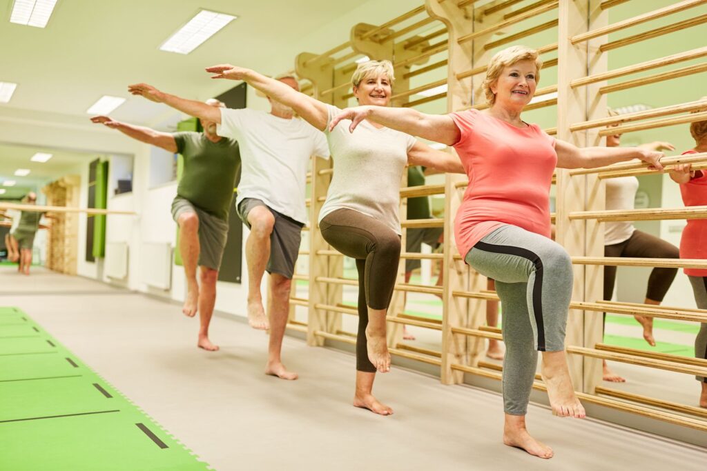 Deux couples de seniors effectuant des exercices réservés aux plus de 60 ans pour renforcer leur équilibre