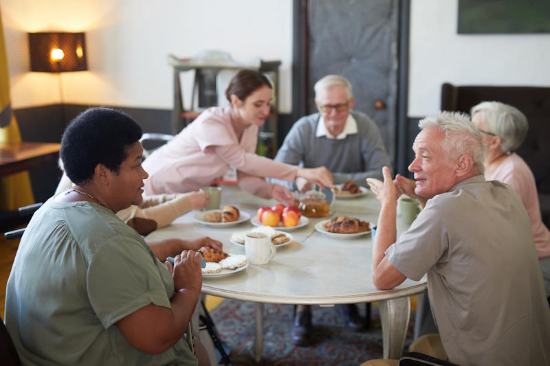 Personnes âgées prenant le petit déjeuner à l'accueil de jour Alzheimer autour d'une table ronde