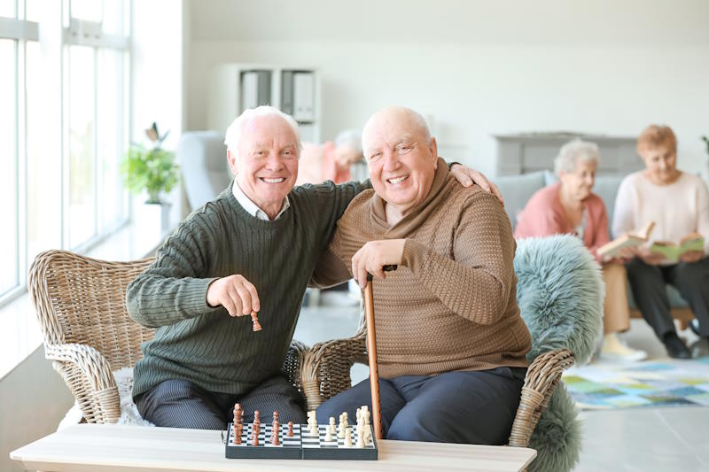 Résidents bénficiaire de l'aide sociale à l'hébergement jouant aux échecs dans le séjour de la maison de retraite