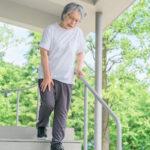 Personne âgée ayant du mal à descendre des marches, l'un des symptômes de la sarcopénie