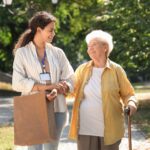 Auxiliaire de vie marchant avec une personne âgée et intervenant dans le cadre du plan d'aide de l'APA