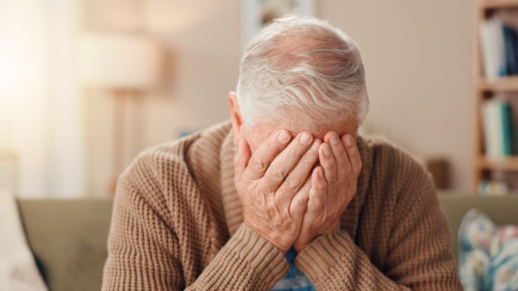 Senior memegang wajahnya di tangannya, pada puncak 5 fase depresi pada lansia