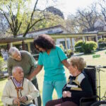 Aide-soignante auprès de résidents dans le parc de la résidence après un placement en EHPAD en urgence