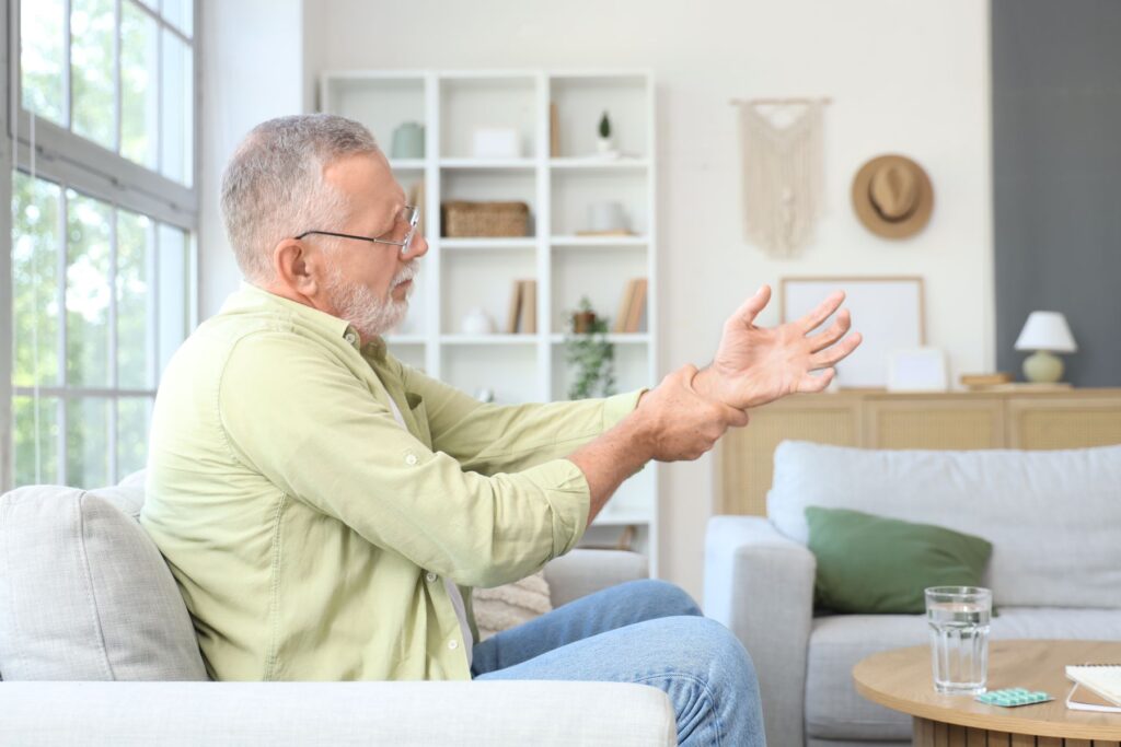 Senior avec une main qui lâche les objets, premier signe de la maladie de Charcot