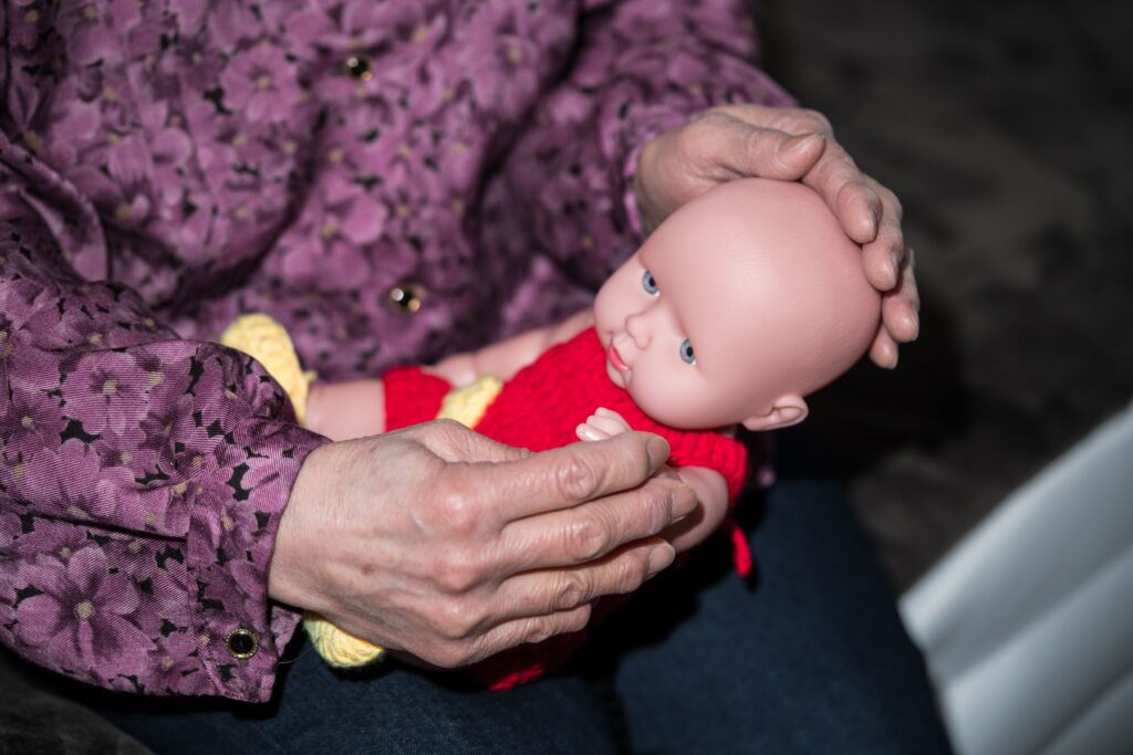 senior Alzheimer prenant soin d'une poupée