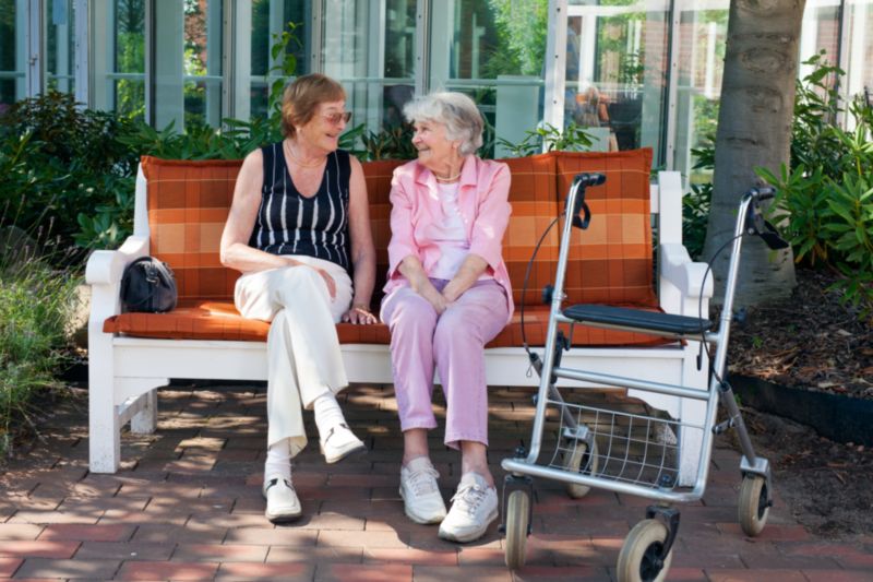 Personnes âgées assises sur un banc et discutant de leur choix d'entrer en maison de retraite