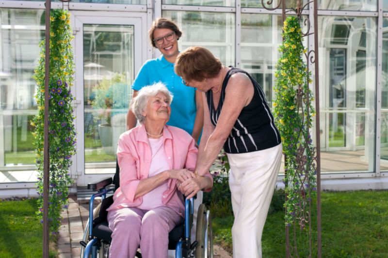 Deux membres du personnel de la maison de retraite souriantes et attentives aux besoins d'une résidente : un gage de qualité de vie en établissement