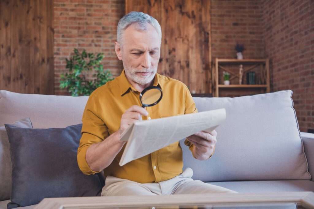 senior atteinte de dmla en ehpad utilisant une loupe pour lire