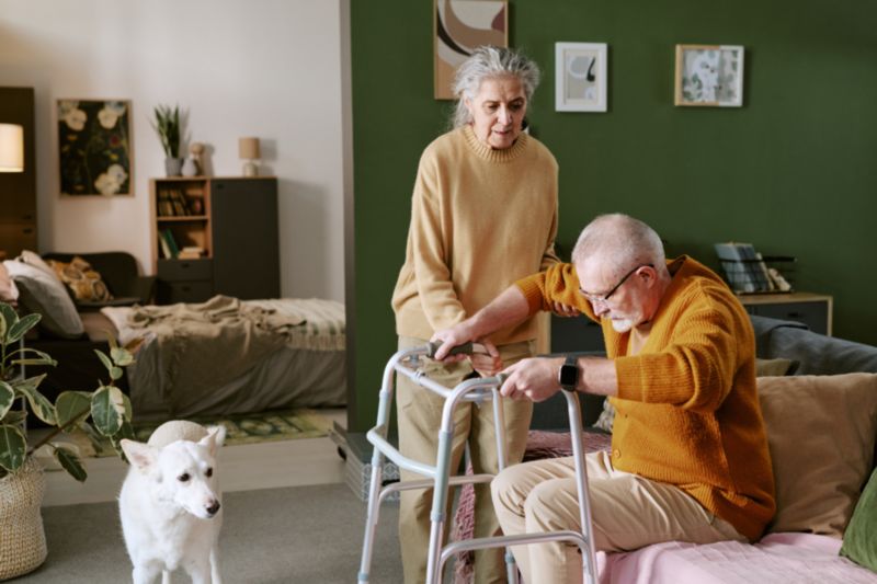 Homme âgé avec déambulateur et sa femme l'aidant en résidence senior